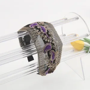 Detailed view of wide mesh headband with gold metallic embroidery and purple velvet paisley pattern.