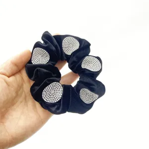 Close-up detail of black velvet scrunchie adorned with sparkling rhinestone clusters.