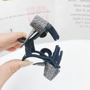 Close-up detail of the elegant black rhinestone bow hair claw clip, sparkling crystals texture.