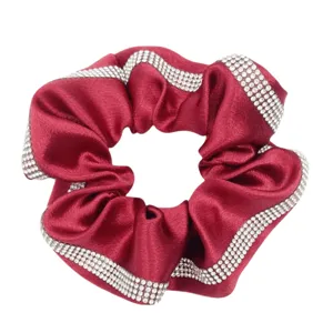 Red satin hair scrunchie with sparkling rhinestone edges, stylish detail for elegant hair style.