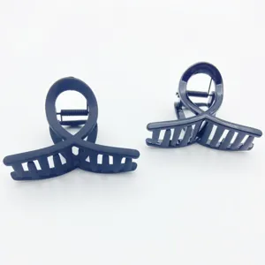 Close-up detail of small matte and glossy cross hair claw clips, elegant daily hair styling.