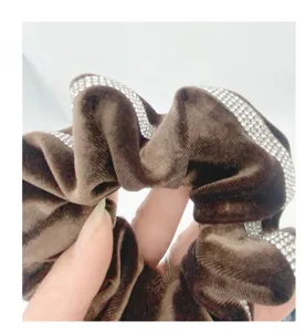 Close-up of brown velvet hair scrunchie with sparkling rhinestone details, elastic hair tie.