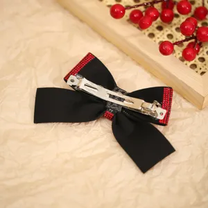 Elegant black velvet hair bow clip with sparkling red rhinestones, perfect festive accessory.