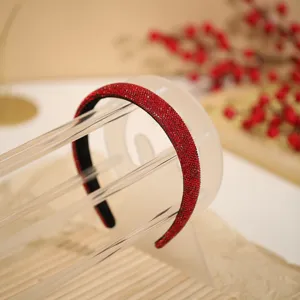 Red rhinestone headband detail showcasing sparkling crystal embellishment on transparent stand.