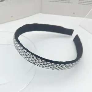 Close-up detail shot of a sparkling rhinestone studded black headband, elegant hair accessory.
