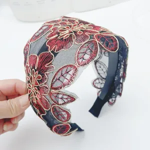 Close-up of black lace headband with detailed red and gold floral embroidery and wide mesh design.