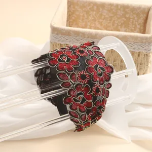 Detailed shot of ethnic embroidered wide headband featuring black mesh and red floral embroidery.
