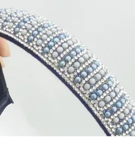 Close-up detail of rhinestone and blue pearl headband, sparkling fashion hair accessory.