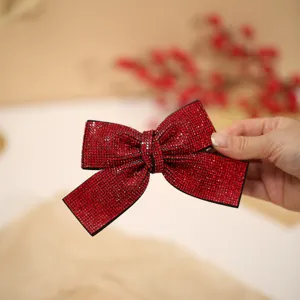 Red rhinestone bow hair clip detail view, sparkling crystals for festive hair styling.
