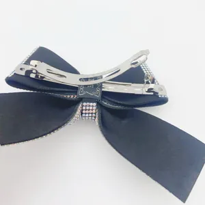 Detail view of a black bow hair clip sparkling with rhinestones and metal spring clasp.
