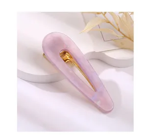 Close up view of the elegant pink acrylic teardrop hair clip with a gold metal snap.