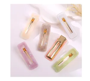 Close-up of colorful acrylic rectangle hair clips with marble pattern and gold metal clips.