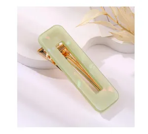 Detailed close-up of light green acrylic rectangular hair clip with gold metal duckbill.