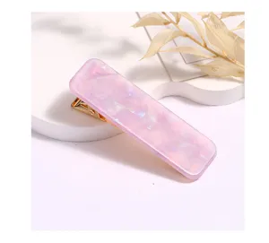 Detailed closeup of a purple marble acrylic hair clip with gold metal clip on white stage.