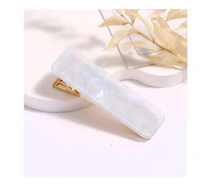 Detailed shot of a rectangular acrylic hair clip with metallic gold alligator clip.