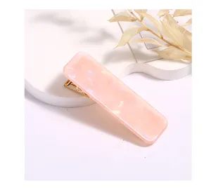 Detailed shot of a pink rectangular acrylic hair clip with a gold duckbill clasp design.