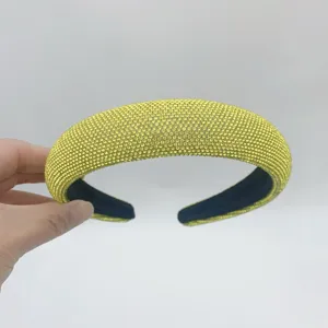 Close-up detail of yellow rhinestone padded headband, sparkling crystal stones, thick sponge design.