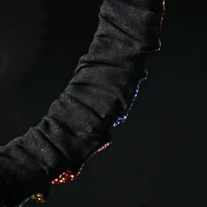 Detailed view of black pleated fabric headband decorated with colorful sparkling rhinestones.