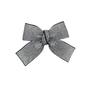Rhinestone bow hair clip detail shot, sparkling crystal studded surface, elegant black base design.