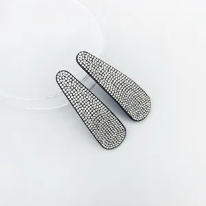 Close-up detail of sparkling rhinestone hair clips on clean white background surface.