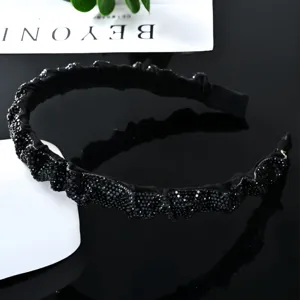 Detailed view of black rhinestone headband with ruffled texture and glittering crystal stones.