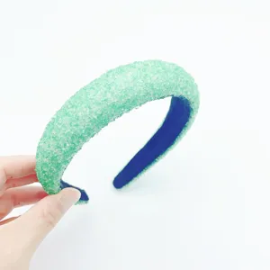Close-up detail view of the sparkling green crystal padded headband with dark blue inner lining.