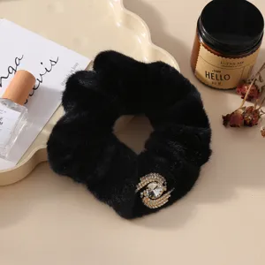 Black plush hair scrunchie detail with sparkling rhinestone ornament for winter style.