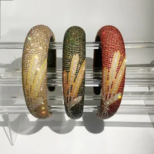 Detailopname van drie sprankelende strass haarbanden met elegante patronen op acrylhouder.