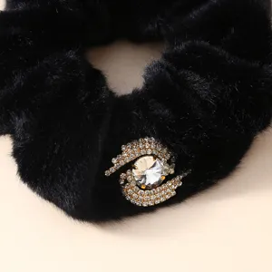 Close-up detail of black plush hair scrunchie with sparkling rhinestone crystal embellishment.