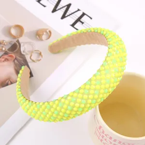Detailed view of vibrant neon yellow and green rhinestone padded headband, fashion accessory.