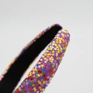 Close-up detail of a wide purple headband covered with colorful sparkling star sequins.