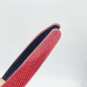 Red rhinestone headband detail close up, sparkling crystal hair hoop for festive party wear.