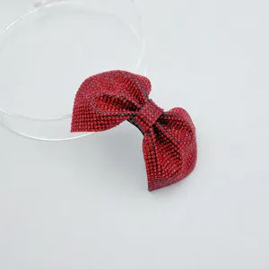 Close-up detail shot of the vibrant red rhinestone bow hair clip, sparkling crystal design.