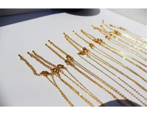 Vista detallada de cadenas de extensión de collar chapadas en oro con cierre de mosquetón.