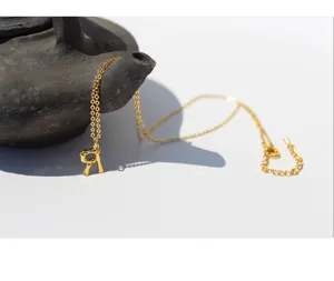 Toma detallada del collar con colgante de letra dorada, joya de cadena estilo bambú único.