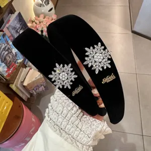 Detailed view of black velvet rhinestone snowflake headband, sparkling crystal details.
