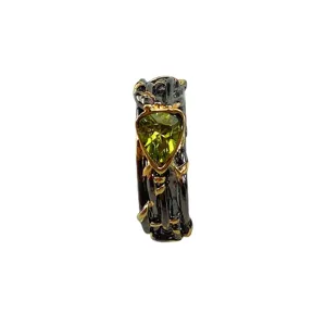 Anillo bicolor con circonita verde talla trillón y textura de rama para estilo moderno.