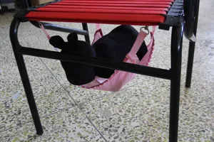 Detail view of breathable pet hammock hanging under chair, pink mesh pet bed for summer.