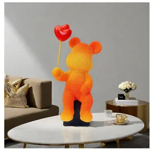 Resin bear figurine holding red heart balloons on a white marble table in a modern living room.