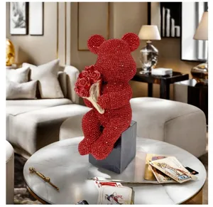 Red rhinestone sitting bear figurine holding rose bouquet, luxury resin home decor ornament.