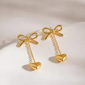 Close-up shot of elegant gold bow and dangling heart earrings showcasing fine metal texture.