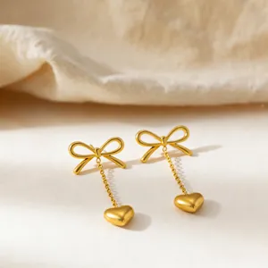 Detail shot of golden bow and hanging heart earrings, minimalist design, elegant metal texture.