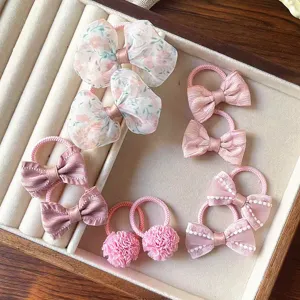 Primo piano dettagliato di simpatici elastici per capelli rosa per bambini, con fiocchi e pon-pon.