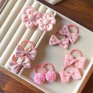 Primo piano dettagliato di simpatici elastici per capelli rosa da bambini con fiocchi e fiori.