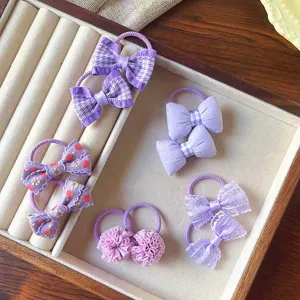 Vista dettagliata di elastici per capelli viola da bambina con graziosi fiocchi e pizzo.