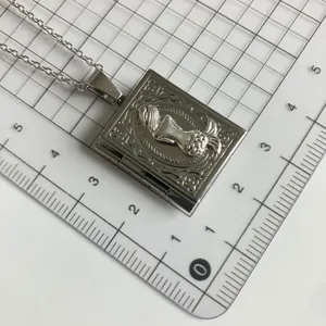Detailed view of the silver book locket necklace featuring intricate embossed relief design on pendant.