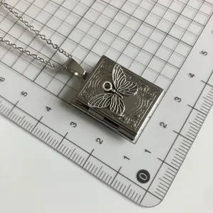 Detailed view of vintage silver book locket necklace featuring a delicate butterfly pendant.