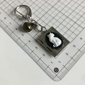 Portachiavi con medaglione a libro argento gotico vintage con cammeo gatto bianco e campanella