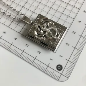 Detailed shot of the silver dragon book locket necklace featuring intricate vintage relief design.