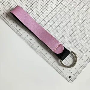 Detail shot of a pink and black neoprene wrist lanyard keychain showing length and build quality.